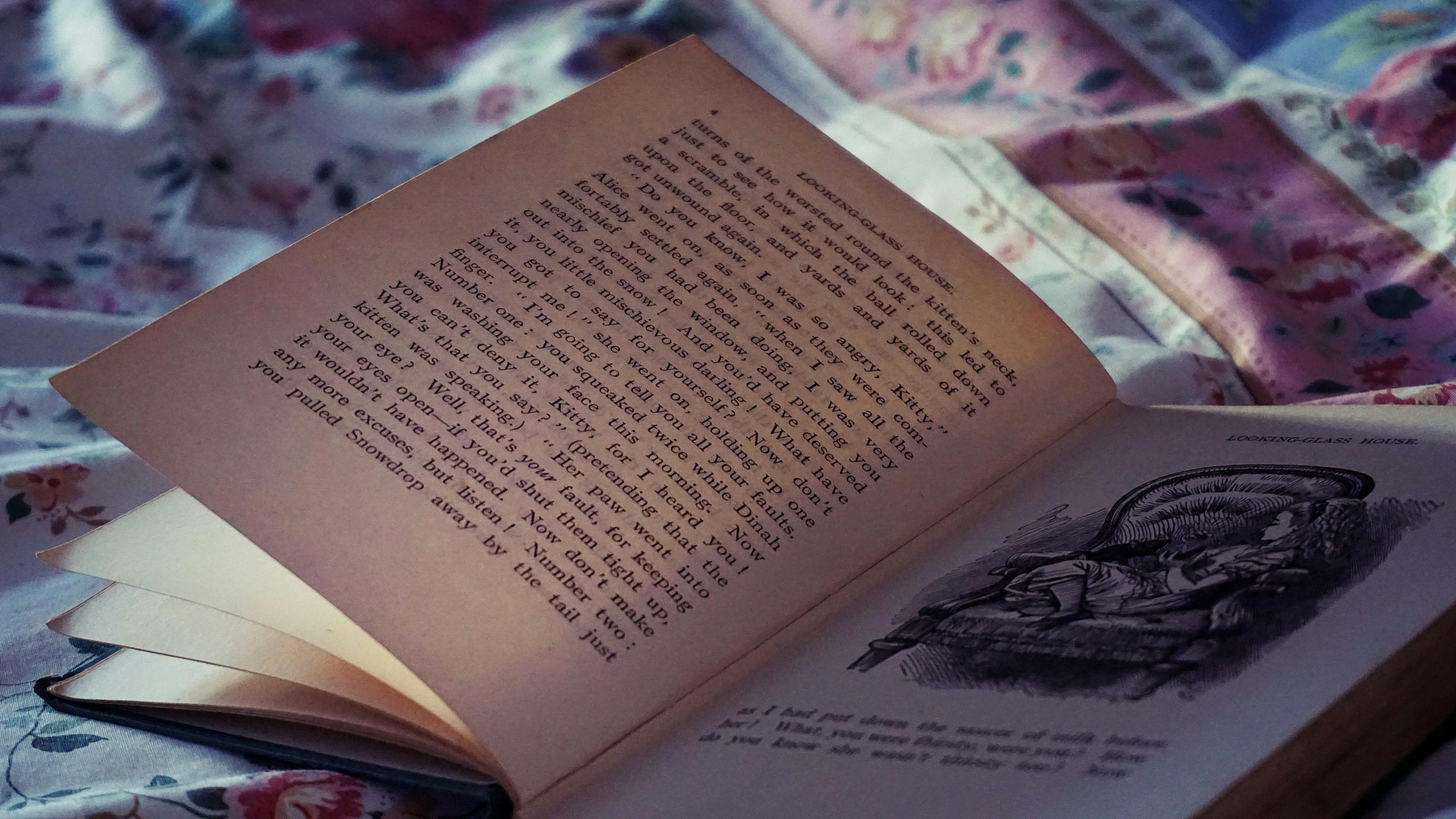 An open vintage book resting on a floral bedspread, evoking a cozy and nostalgic atmosphere.